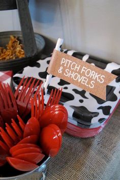 red forks and shovels are in a bowl on a table with cow print napkins