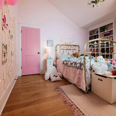 A two-panel pink door in a pink little girl's bedroom with a brass bed, stuffed animals and rope lights on the walls.