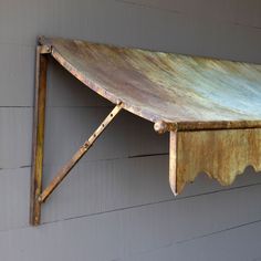 an old metal shelf hanging on the side of a building with wood slats attached to it