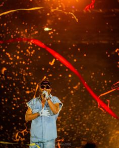 a man standing on top of a stage with confetti in his hand and streamers flying around him