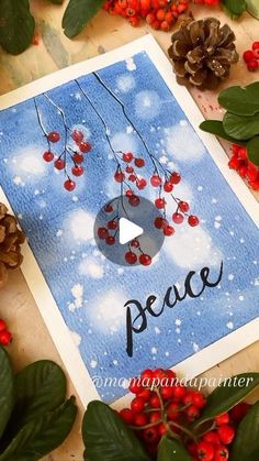 a christmas card with the words peace surrounded by holly berries and pine cones, on a wooden surface