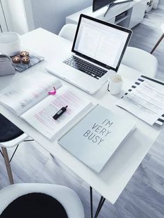 a white desk with two laptops and papers on it