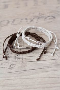 three white and brown bracelets sitting on top of a wooden floor