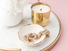 a candle, bowl and chain on a marble tray