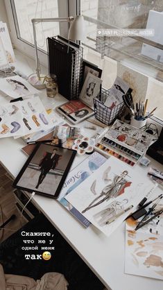 the desk is cluttered with art supplies and paper on it's surface,