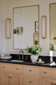 a bathroom vanity with two sinks and large mirror above it, along with vases on the counter