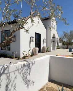 a white house with an olive tree in the front yard