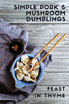 a blue bowl filled with dumplings next to chopsticks on top of a wooden table