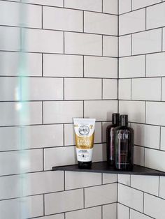 two bottles of hand cream and lotion sitting on a shelf in a tiled bathroom