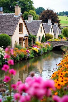 flowers line the bank of a river in front of small houses with bridges over them