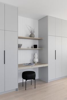 an empty room with white cabinets and black chair in the center, on top of a hard wood floor