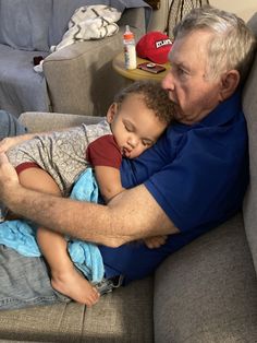 an older man sitting on a couch holding a small child with his arm around him