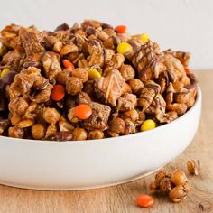 a white bowl filled with candy cornflakes and candies on top of a wooden table