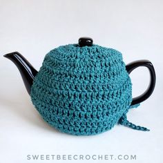 a crocheted tea pot cover with a black handle