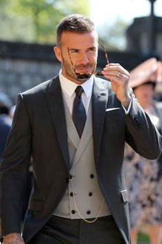 a man in a suit and tie is holding something to his face while walking down the street