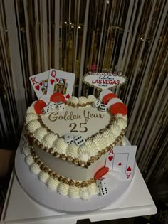 a heart shaped cake decorated with playing cards and gambling chips on a white table top