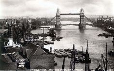 an old black and white photo of the tower bridge in london with boats on the river below