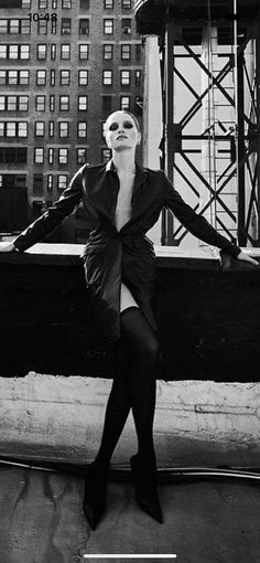 a black and white photo of a woman posing in front of a plane