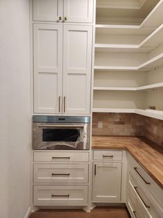 an empty kitchen with white cabinets and wood flooring