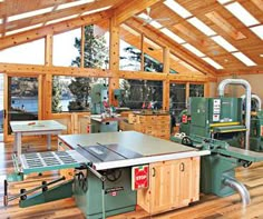 a table sawing in a wood shop with lots of windows and wooden flooring