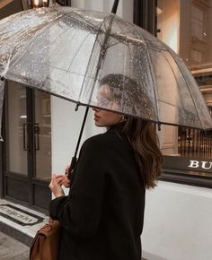 a woman walking down the street while holding an umbrella over her head with water droplets on it