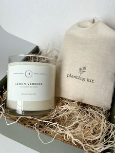 a candle in a box next to a drawstring bag