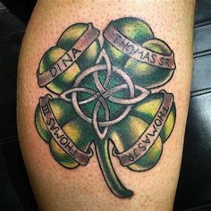 a shamrock tattoo on the leg with ribbons around it