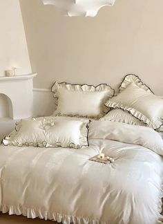 a bed with white sheets and pillows on top of it in a room next to a fireplace