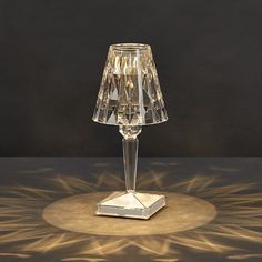 a clear glass table lamp sitting on top of a table