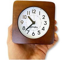 a hand holding a wooden clock with numbers on it