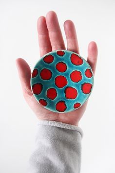 a hand holding a blue and red object in it's palm