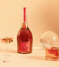 a bottle of wine sitting on top of a table next to two glasses filled with liquid