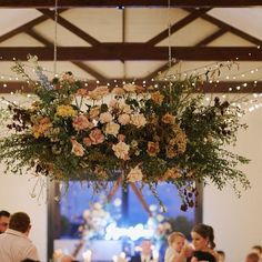 a chandelier with flowers hanging from it's ceiling at a wedding reception