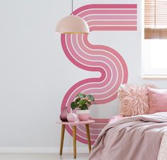 a bedroom with pink and white decor on the wall next to a small table, lamp and bed