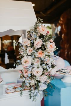 a bouquet of pink flowers sitting on top of a blue table next to donuts