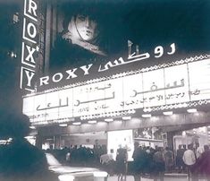 an old movie theater with people standing in front of it and the marquee lit up