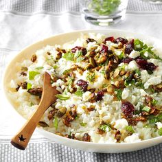 a white bowl filled with rice, nuts and celery on top of a table