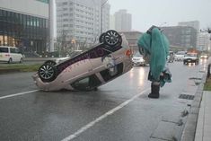 a car that is upside down on its side in the street with it's hood up