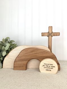 a wooden cross sitting on top of a table next to a plaque that says it is not there