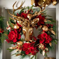 a gold deer head decorated with red flowers and greenery