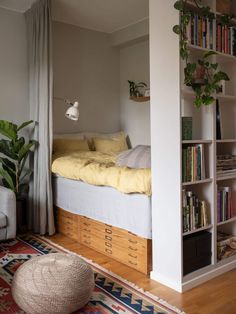 a bed sitting next to a book shelf filled with books on top of a wooden floor