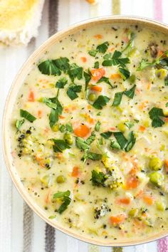 a bowl of soup with carrots, broccoli and other vegetables