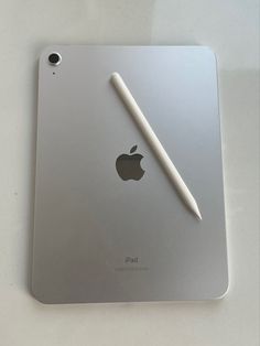 an ipad with a pen sitting on top of it's back cover next to the apple logo