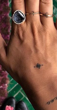 a woman's hand with a ring on it and a star tattoo on the middle finger