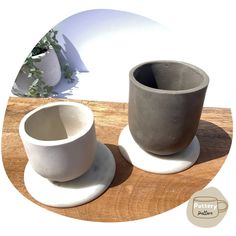 two cement cups sitting on top of a wooden table