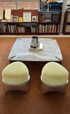 two stools sitting on top of a table in front of a bookshelf