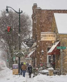 two people walking down a snowy street in front of a coffee shop