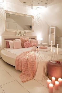 a white bedroom with candles on the floor and a round bed in the corner,