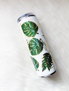 a white can with green leaves on it sitting on top of a fur covered floor