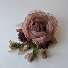 a flower that is sitting on top of a white surface with leaves and flowers around it